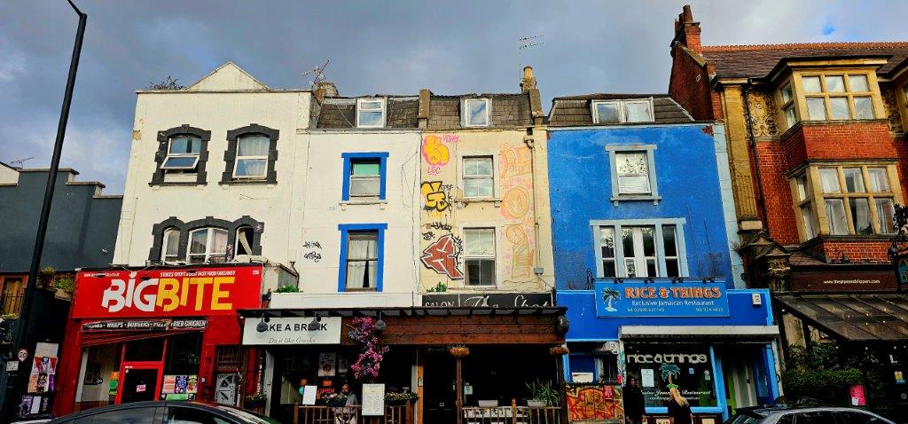 Row of independent food businesses on Stokes Croft including Big Bite, Take a Break Greek cafe and Rice and Things Jamaican restaurant