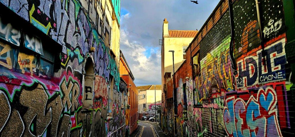 Narrow lane with walls covered top to bottom in colourful graffiti