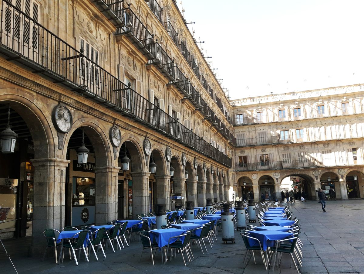 Cafe tables beneath the stone arcades of the Plaza Mayor in Salamanca