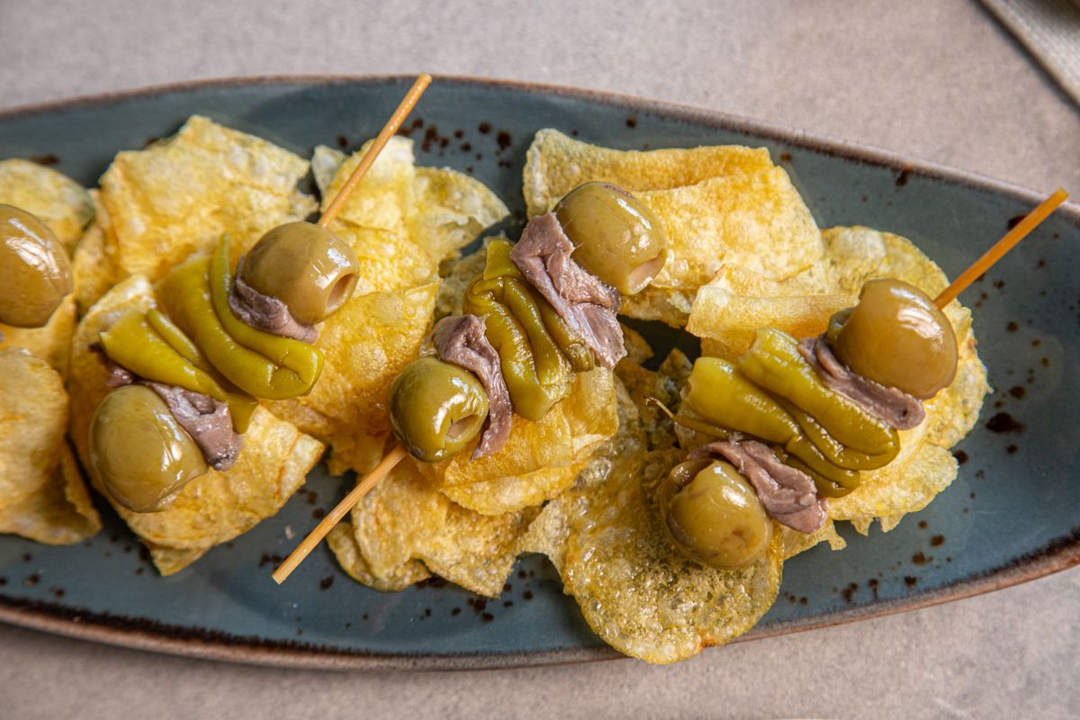 Gilda pintxos of olives, anchovies and peppers on skewers, served on a plate